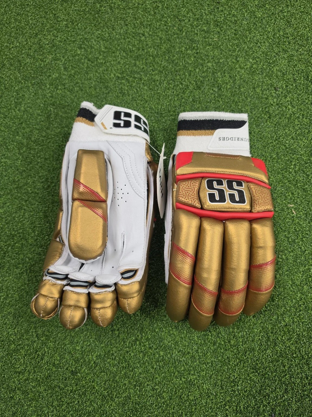 Top view of SS Super Test RCB IPL cricket batting gloves on green turf highlighting gold thumb protection and SS wrist cuff