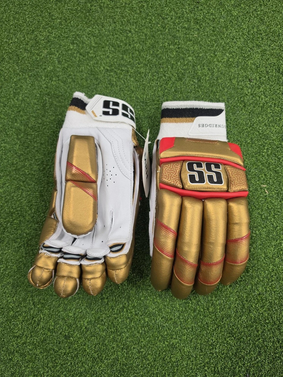 Top view of SS Super Test RCB IPL cricket batting gloves on green turf highlighting gold thumb protection and SS wrist cuff