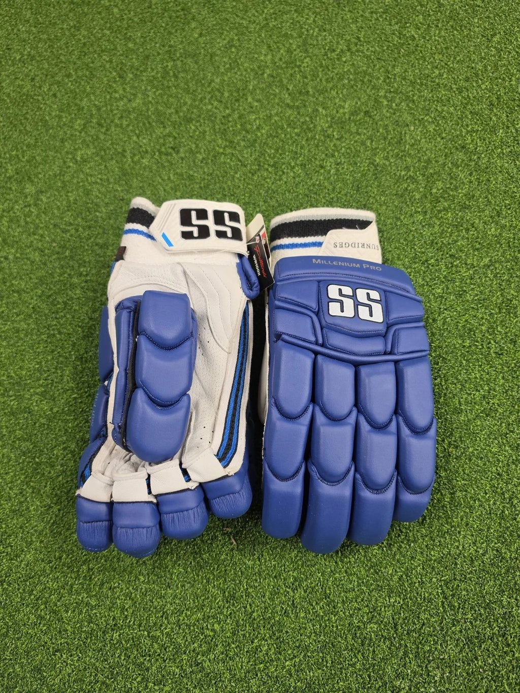 Flat top-down view of blue and white SS TON Millennium Pro adult cricket batting gloves resting on artificial turf