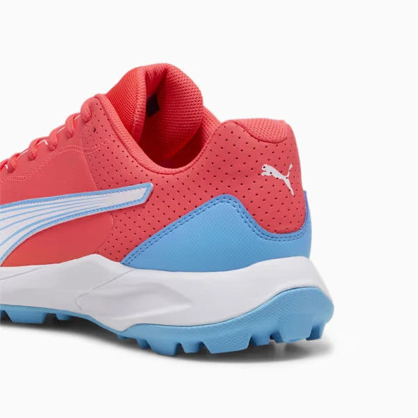 Rear angle view of a red and luminous blue Puma 24 FH Rubber Cricket Shoe showing padded red heel collar, white Puma cat logo, light blue heel counter, and rubber studded outsole.