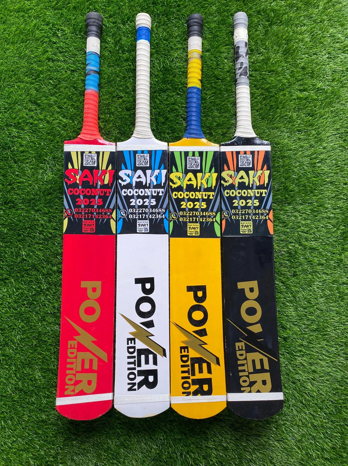 Four Saki Power Edition Srilankan Willow Coconut cricket bats in various colors, displayed on green grass.