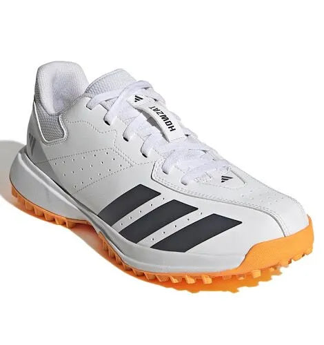 Front angled view of a white Adidas Howzat cricket shoe with grey stripes and an orange outsole.