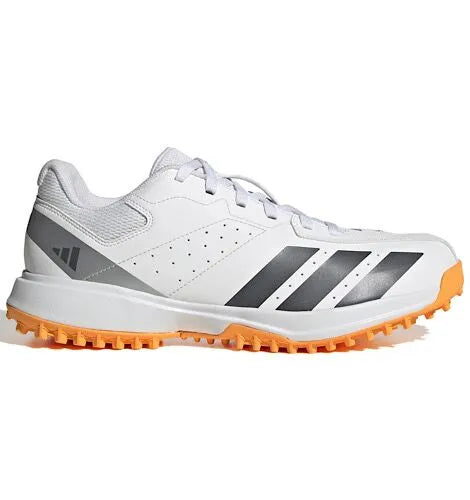 Side view of a white Adidas Howzat cricket shoe with grey stripes and an orange outsole.