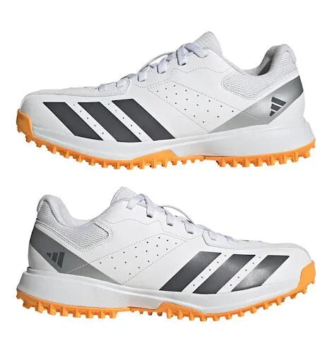 Two side views of white Adidas Howzat cricket shoes with grey stripes and orange outsoles.