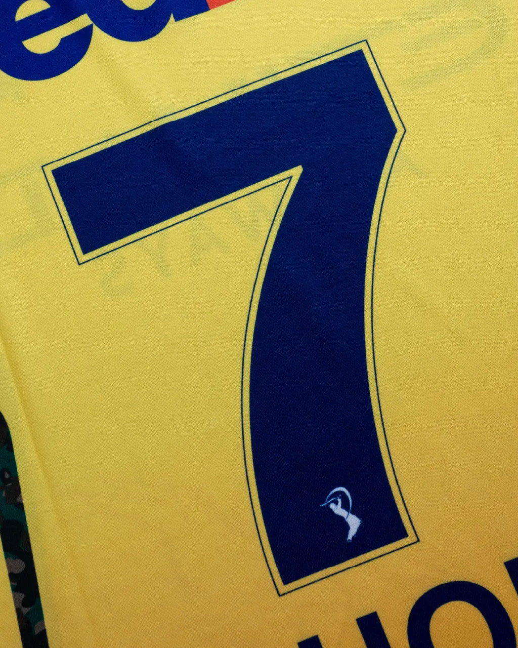 Close-up of the blue number 7 print on a yellow Chennai Super Kings jersey.