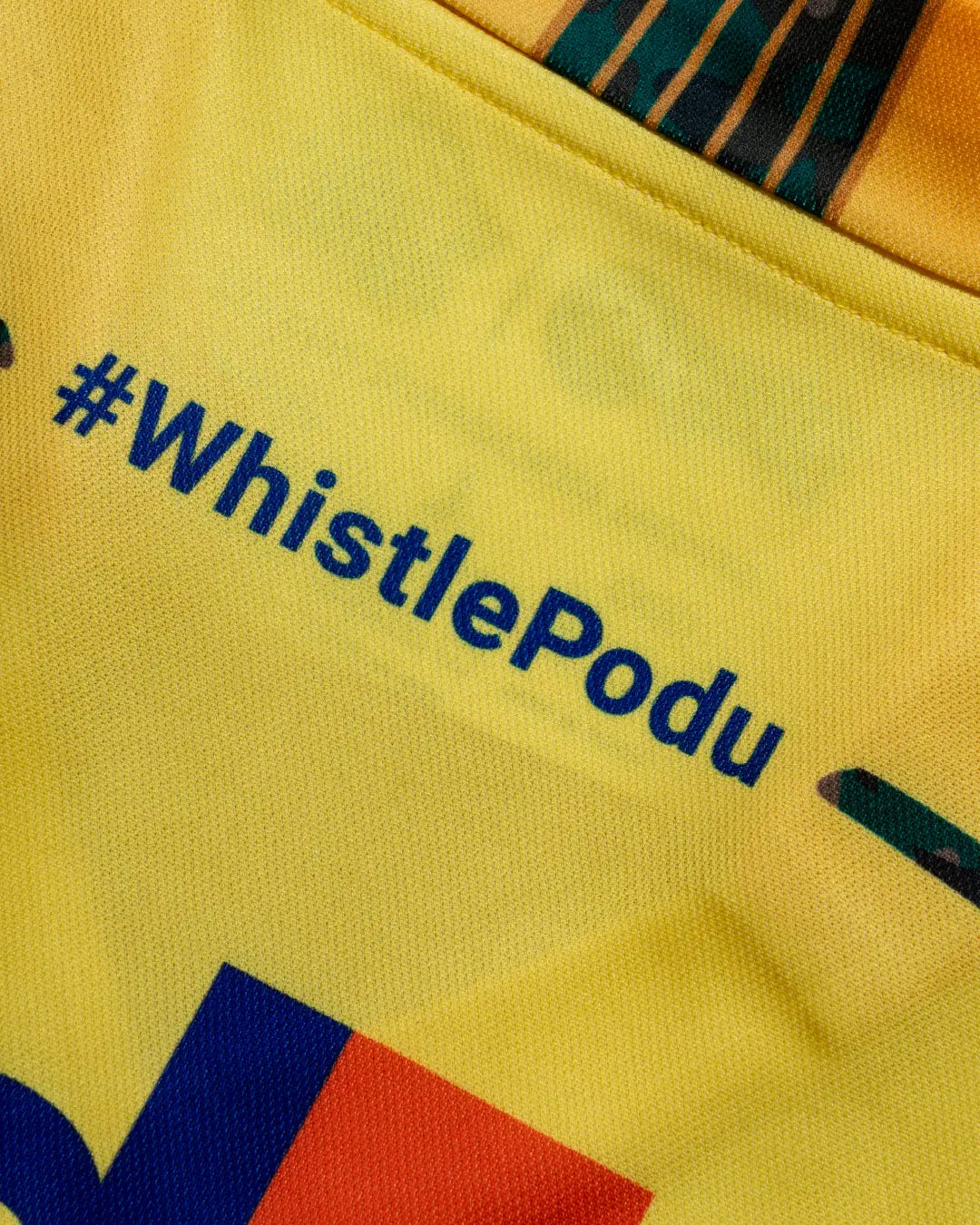 Close-up of the #WhistlePodu slogan on a yellow Chennai Super Kings jersey.