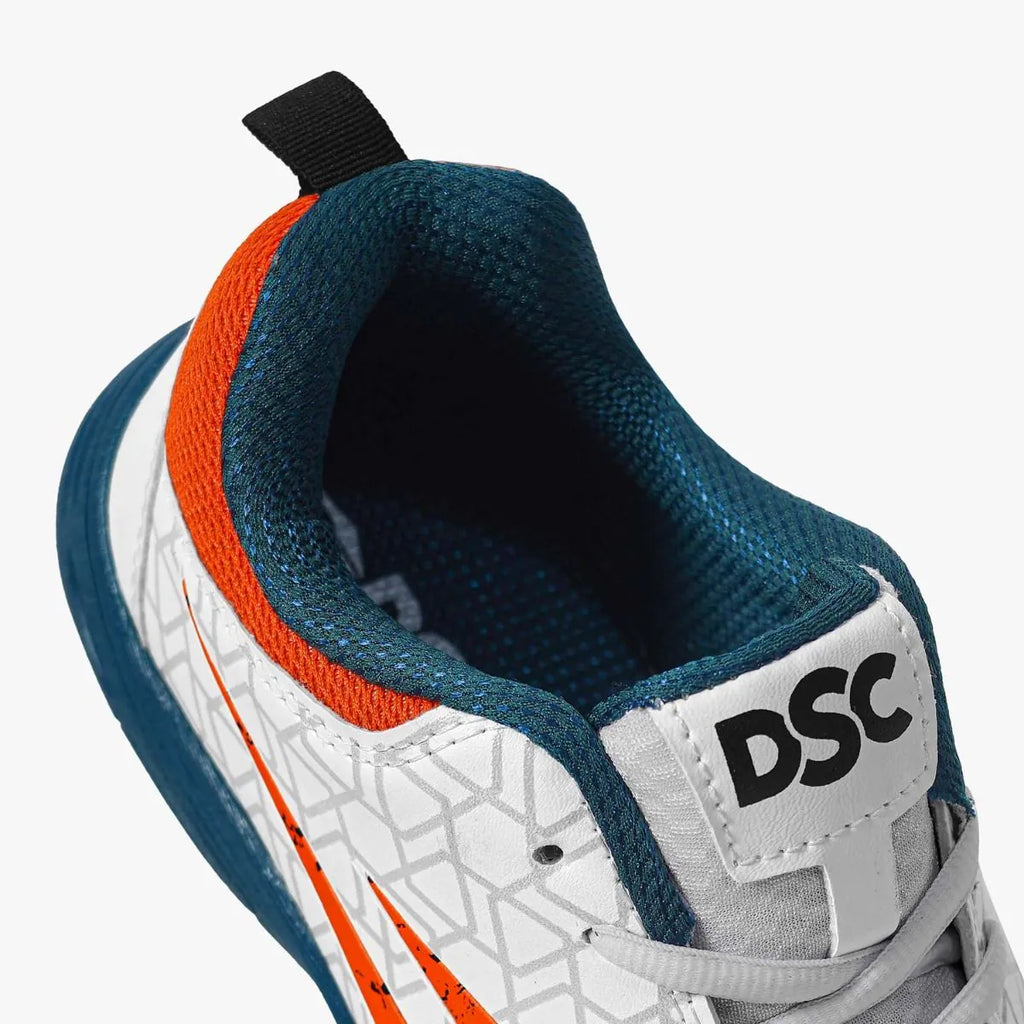 Close-up view of DSC Belter cricket shoe heel collar and tongue featuring orange accent trim and black DSC logo.