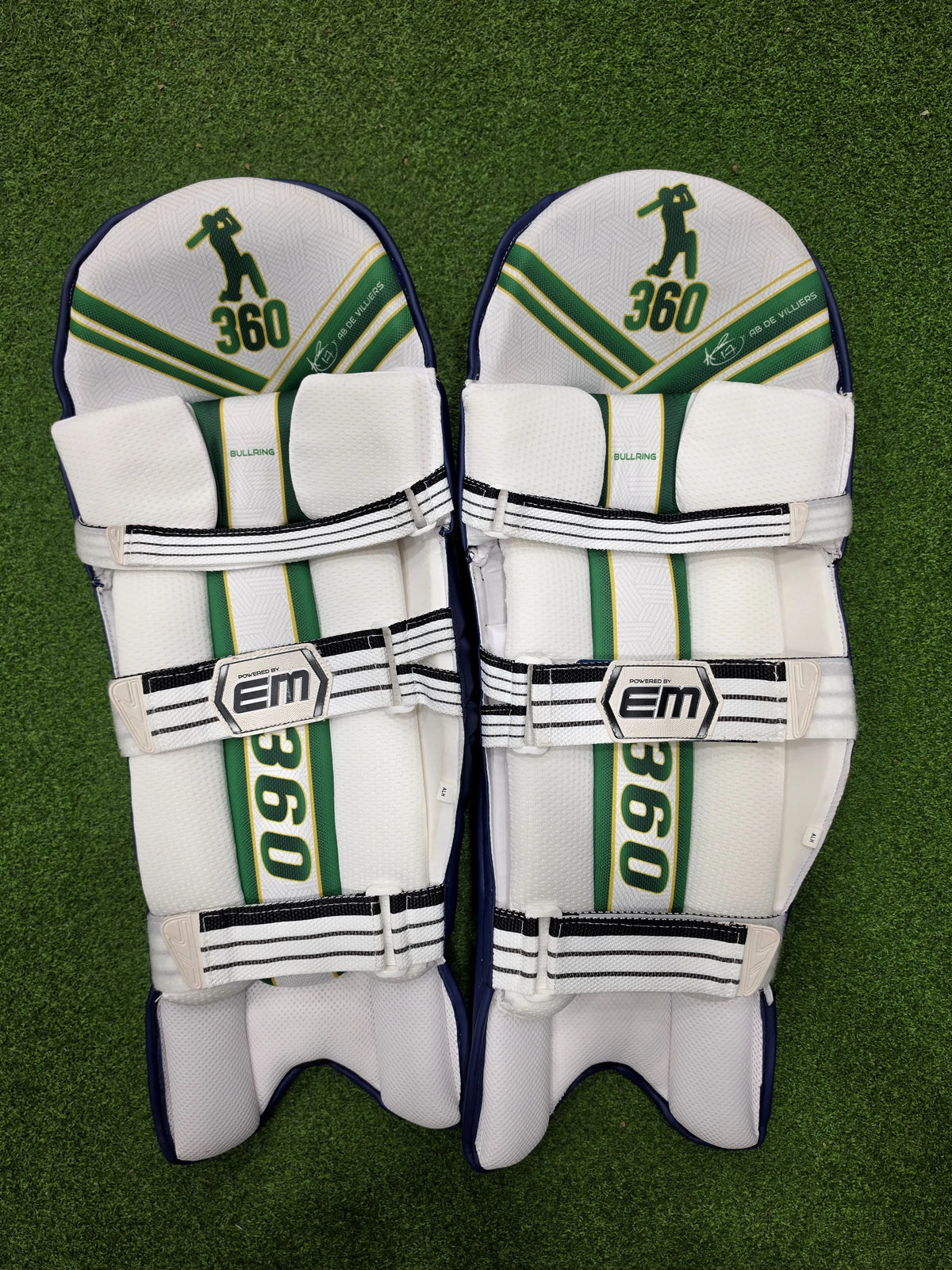 Inner padding and straps of EM 360 Bull Ring cricket batting pads on green artificial turf.