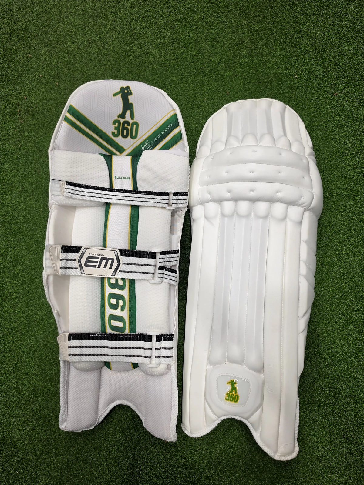 Front face and inner padded back view of EM 360 Bull Ring adult white cricket batting pads on artificial grass on Alberta.