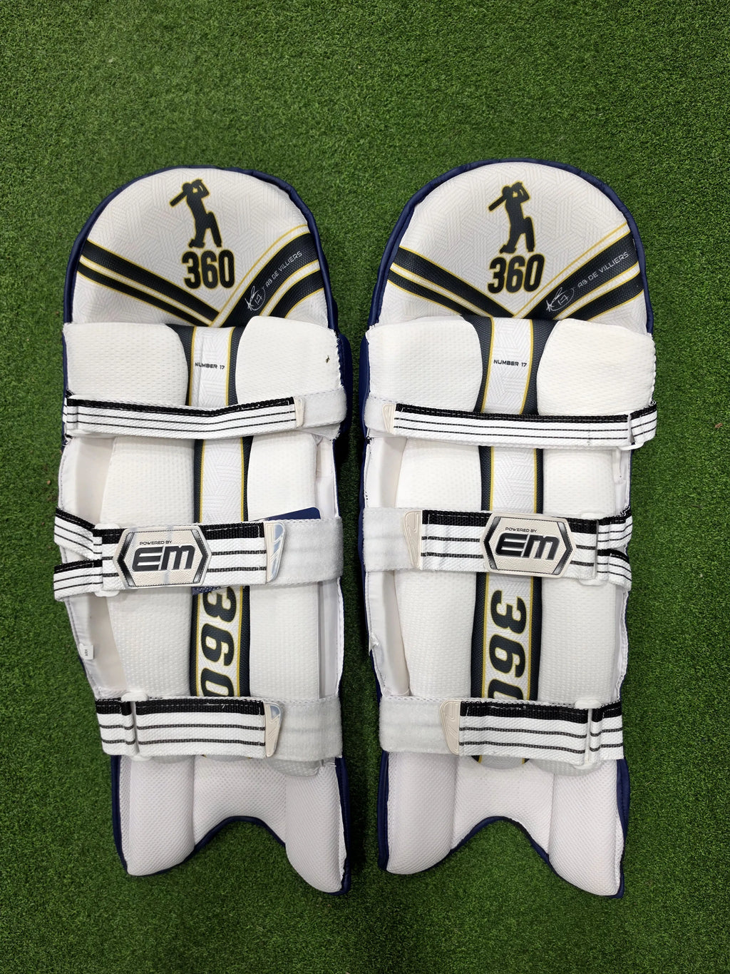 Inner back padded view of EM 360 No 17 adult navy blue cricket batting pads on artificial grass on Alberta.