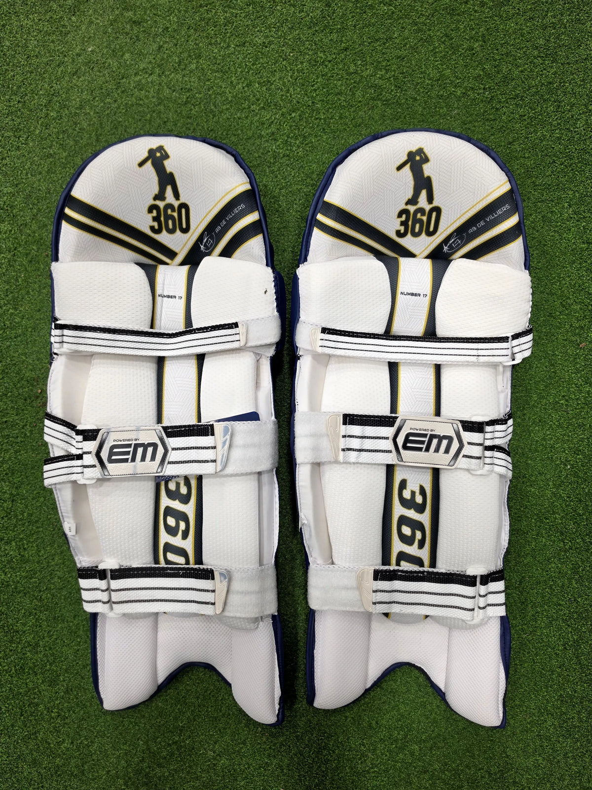 Inner back padded view of EM 360 No 17 adult navy blue cricket batting pads on artificial grass on Alberta.