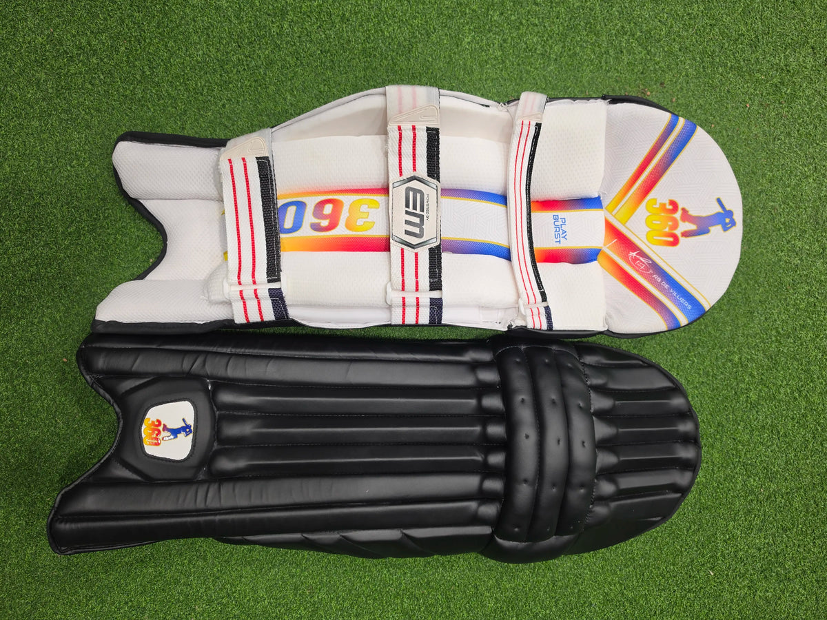 Front and inner back view of EM 360 Play Burst black cricket batting pads on green artificial turf.