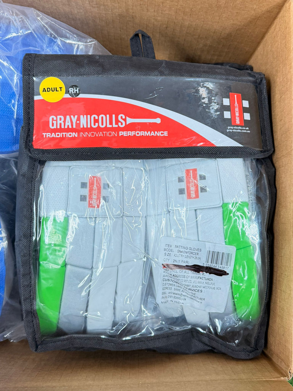 White and green Gray-Nicolls Enforcer adult batting gloves inside a black and transparent retail pouch.