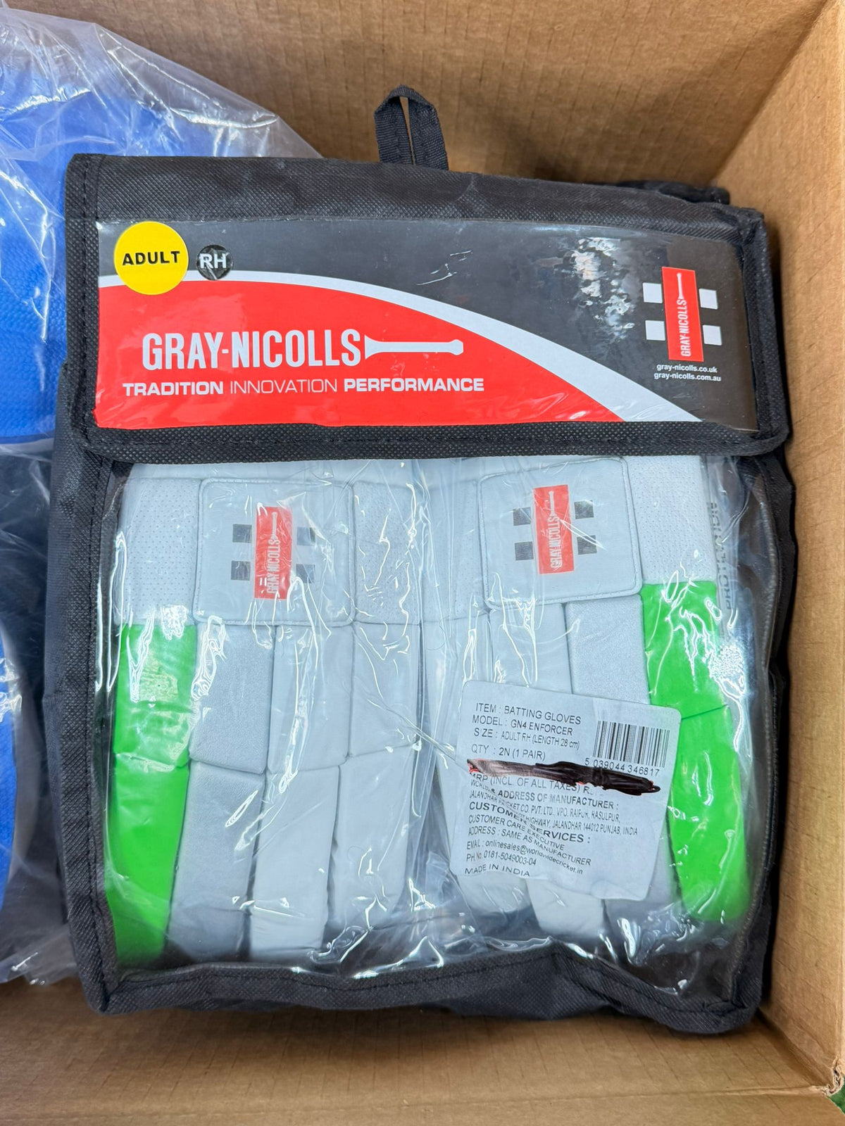 White and green Gray-Nicolls Enforcer adult batting gloves inside a black and transparent retail pouch.