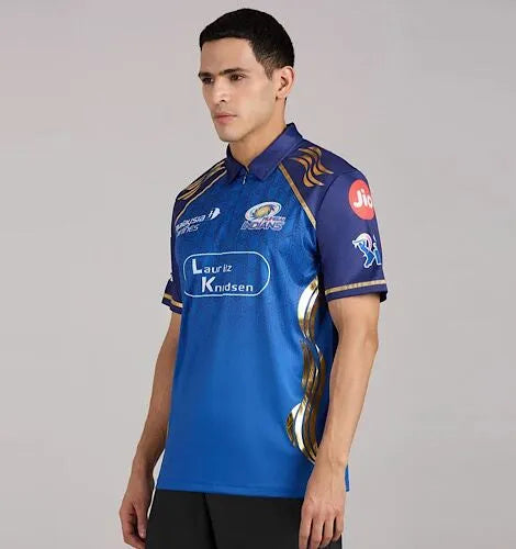 Model wearing a blue Mumbai Indians cricket jersey with gold detailing, viewed from a side angle.