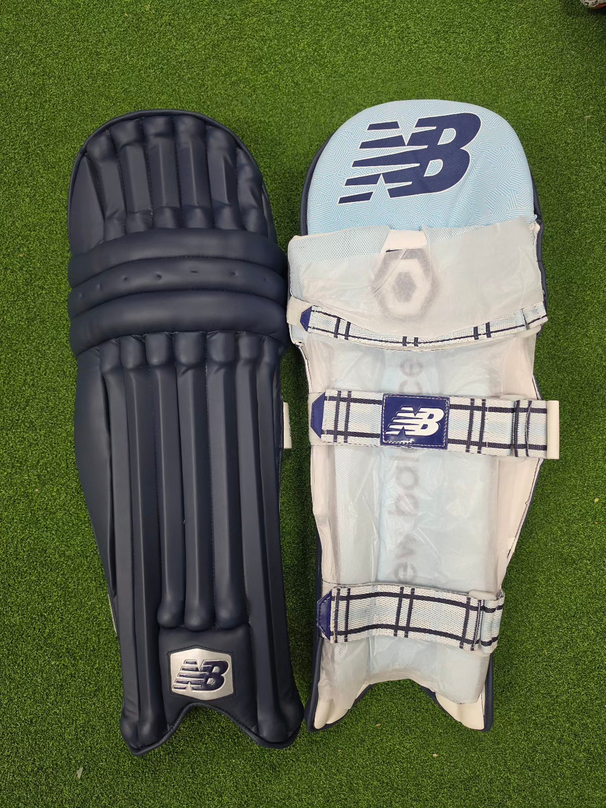 Navy blue New Balance TC 8i batting pads showing the front and inner padding side by side on green turf.
