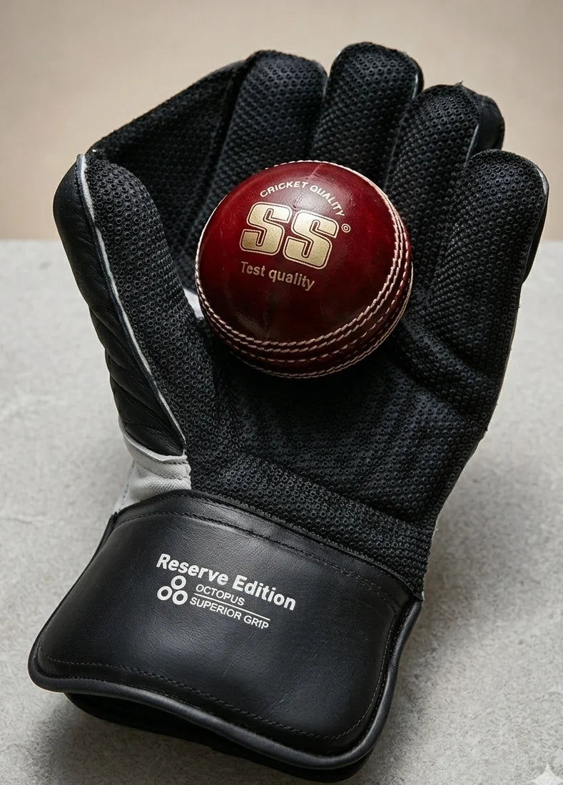 Black Reserve Edition wicket keeping glove palm holding a red SS cricket ball.
