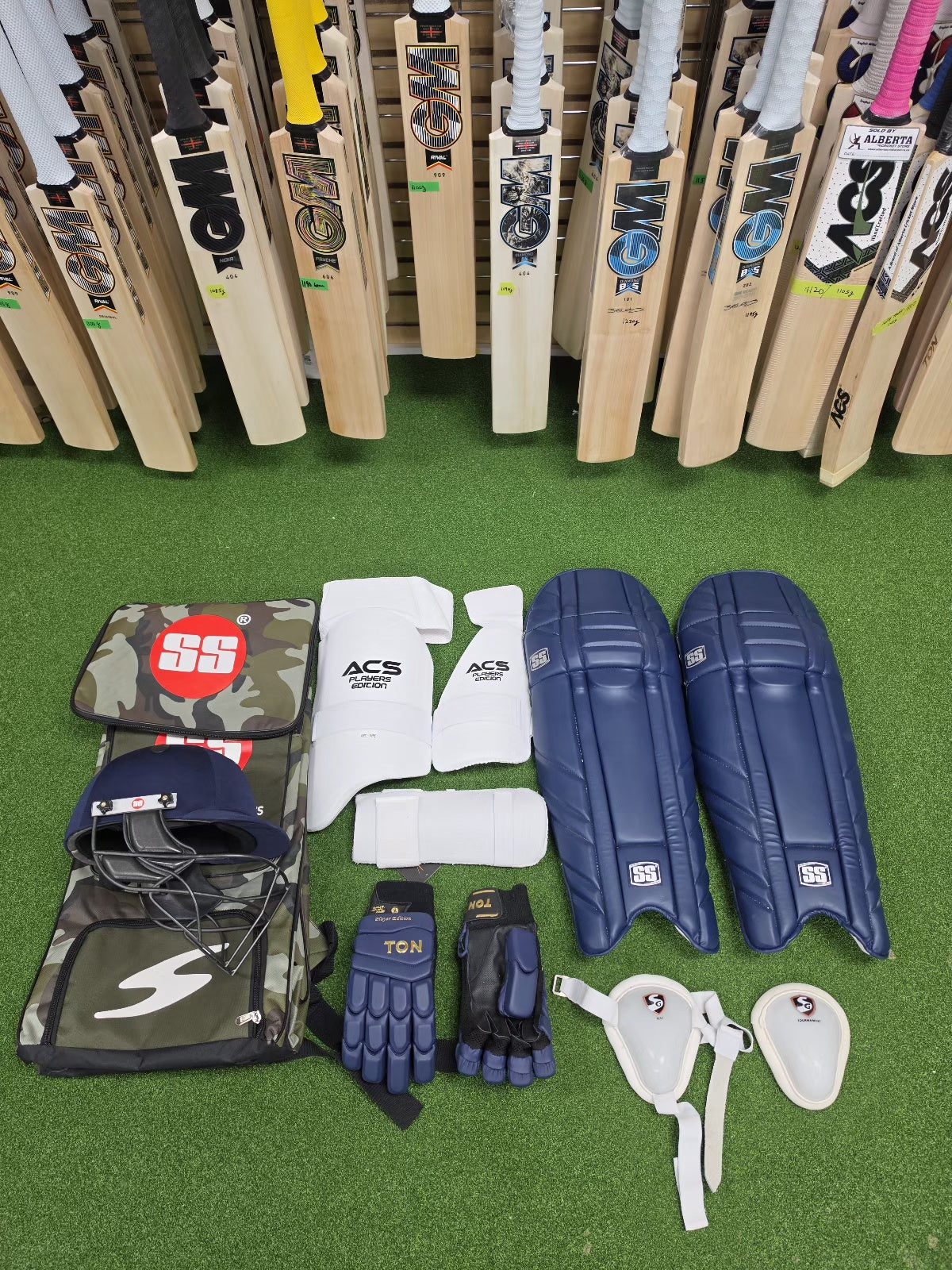 SS full cricket kit with navy blue batting pads and GM cricket bats display