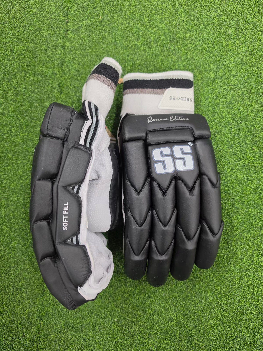 Outer casing view of charcoal black and white SS Ton Reserve Edition Cricket Batting Gloves on green grass at Alberta Cricket Store.