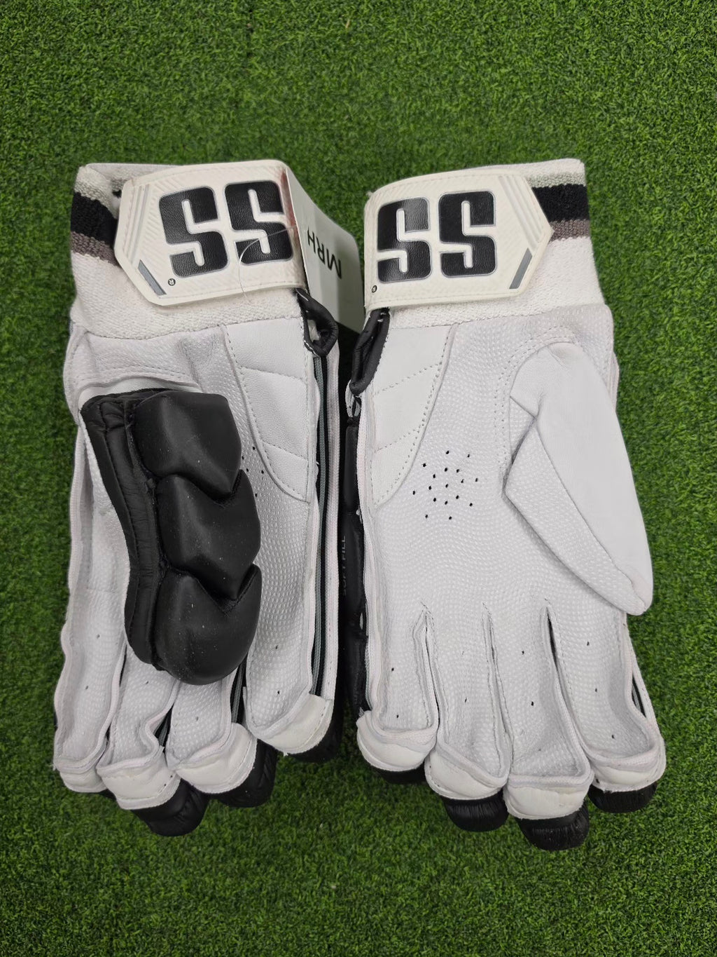 Palm and side view of black and white SS TON Reserve Edition batting gloves on green turf.
